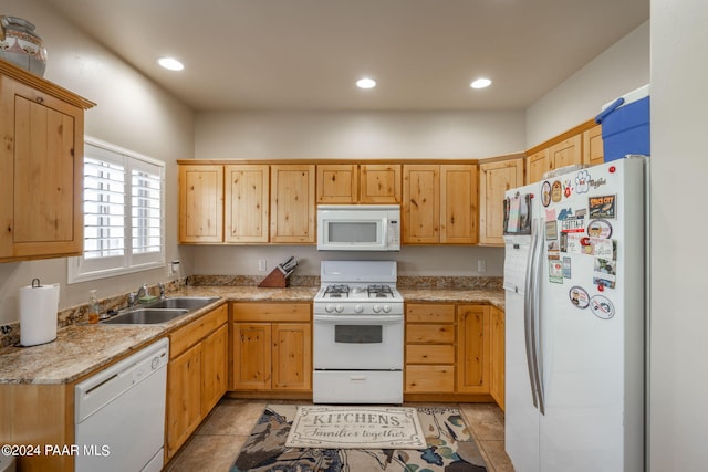 kitchen with light brown cabinetry, sink, light tile patterned floors, and white appliances