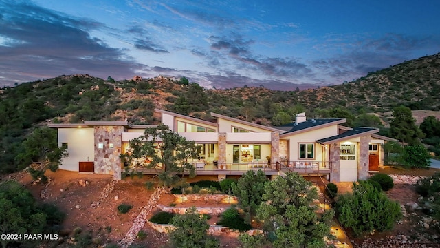 back house at dusk with a deck with mountain view