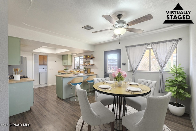 dining space featuring a textured ceiling, washer / clothes dryer, and wood finished floors