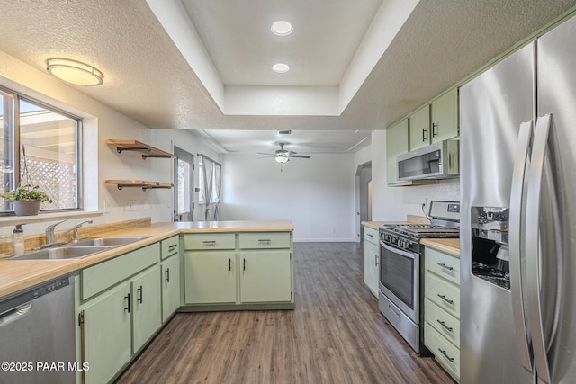 kitchen featuring appliances with stainless steel finishes, light countertops, a sink, and green cabinets