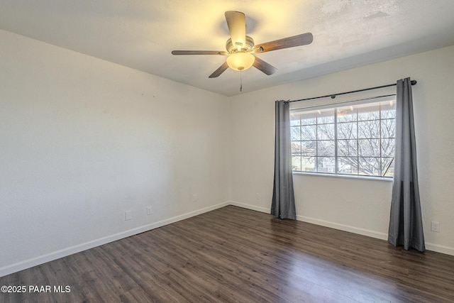 unfurnished room with a ceiling fan, baseboards, and dark wood-style flooring