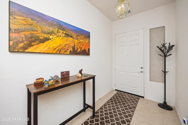 foyer featuring light tile patterned floors, baseboards, and a chandelier