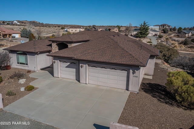 view of front of home featuring driveway, roof with shingles, a garage, and stucco siding