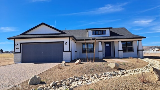 view of front of house with covered porch, brick siding, decorative driveway, and an attached garage