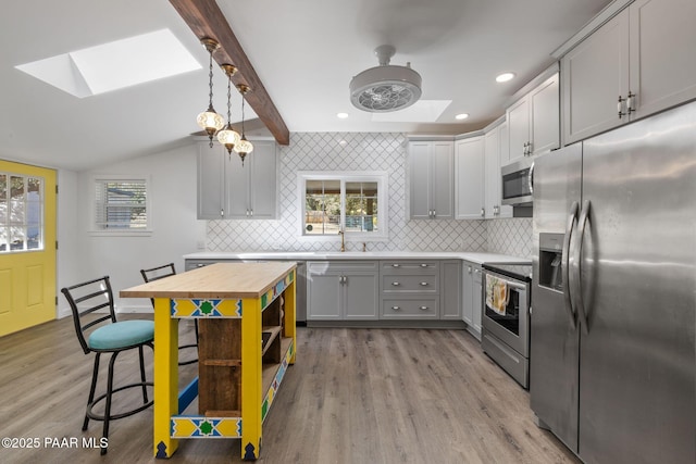 1467 N Vyne St, Prescott, AZ 86305 - kitchen featuring lofted ceiling with skylight, appliances with stainless steel finishes, light wood-type flooring, gray cabinetry, and backsplash
