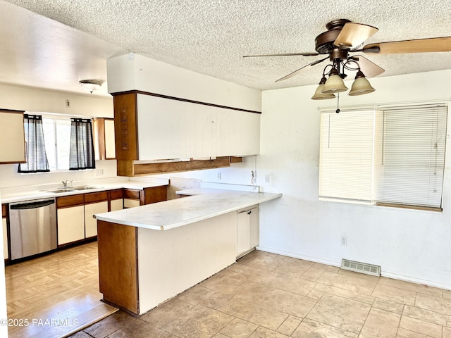 kitchen featuring a textured ceiling, kitchen peninsula, and dishwasher