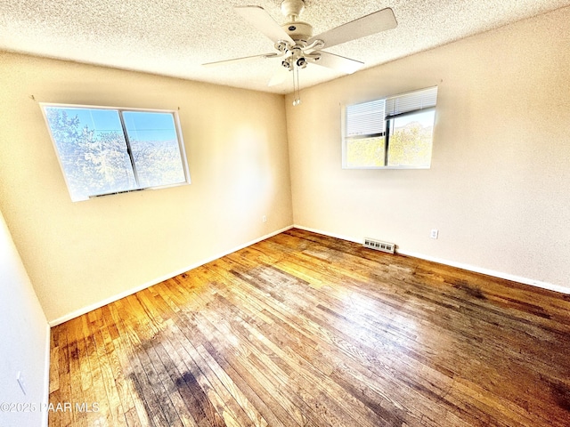 spare room featuring hardwood / wood-style flooring, a healthy amount of sunlight, and a textured ceiling