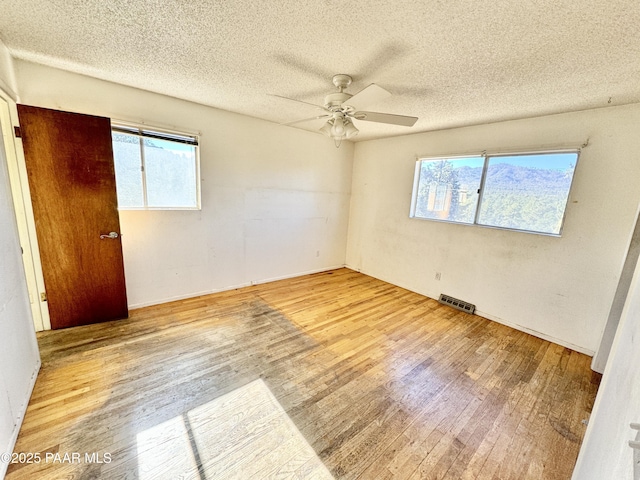 unfurnished bedroom featuring ceiling fan, a textured ceiling, and light wood-type flooring