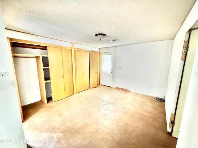 unfurnished bedroom featuring multiple closets and a textured ceiling