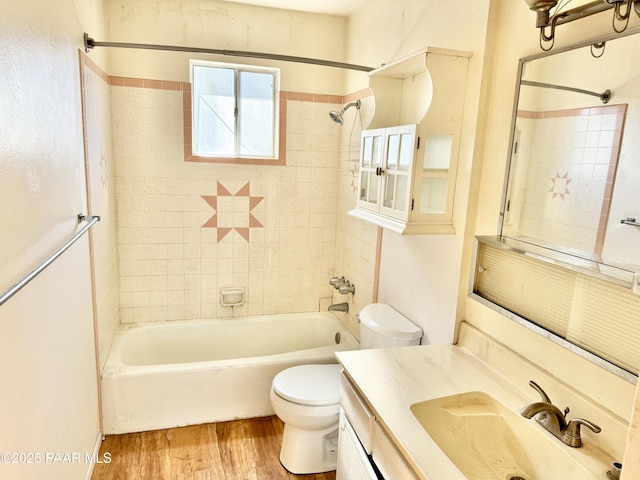 full bathroom with hardwood / wood-style flooring, tiled shower / bath, vanity, and toilet