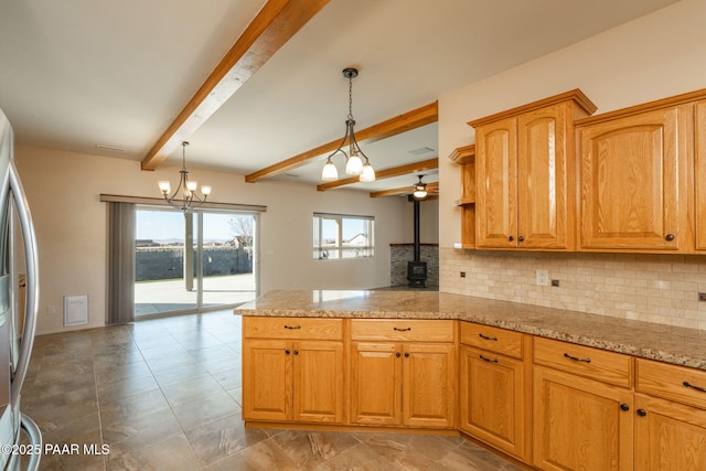 kitchen with kitchen peninsula, pendant lighting, light stone countertops, a wood stove, and beamed ceiling