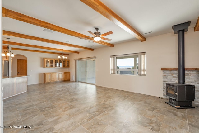 unfurnished living room with a wood stove, ceiling fan with notable chandelier, and beamed ceiling