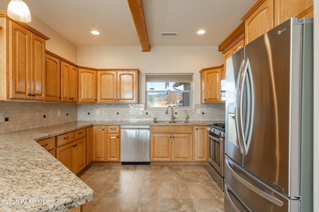 kitchen featuring sink, light stone counters, decorative backsplash, and appliances with stainless steel finishes