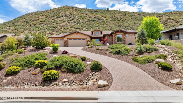 1138 N Cloud Cliff Pass, Prescott Valley, AZ 86314 - view of front facade featuring stone siding, a mountain view, a garage, and curved driveway
