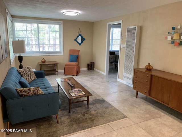 sitting room with a heating unit, light tile patterned flooring, a textured ceiling, and baseboards