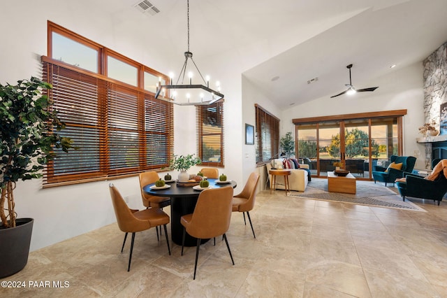 dining space featuring high vaulted ceiling and ceiling fan with notable chandelier