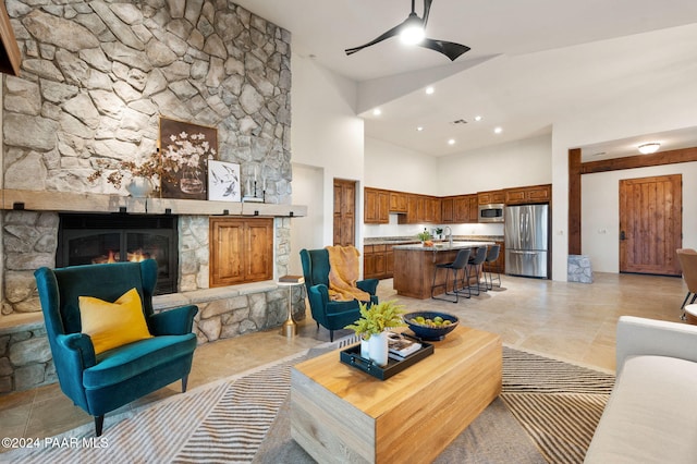 tiled living room with a stone fireplace, sink, and a high ceiling