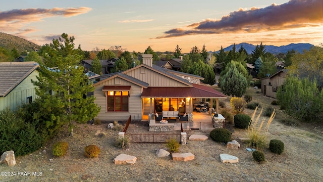 back house at dusk featuring outdoor lounge area, a mountain view, and a patio area