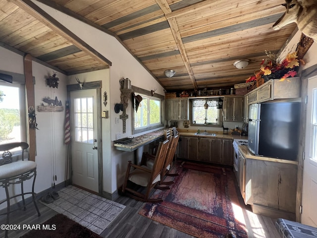 kitchen featuring stainless steel fridge, vaulted ceiling with beams, dark wood-type flooring, and a healthy amount of sunlight