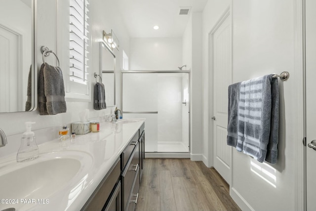 bathroom with hardwood / wood-style flooring, vanity, and a shower with door