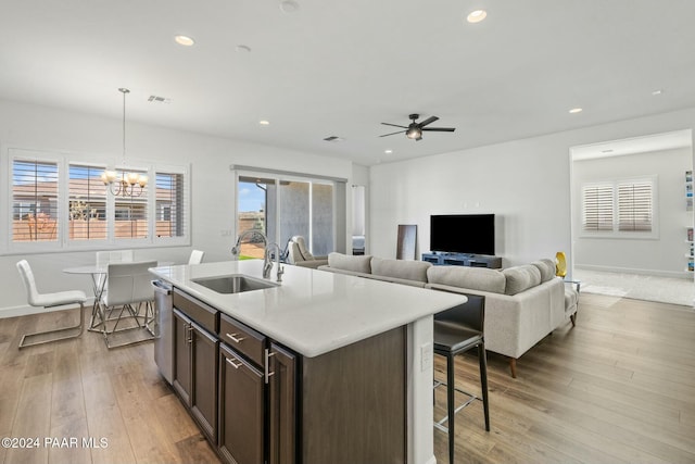 kitchen featuring pendant lighting, sink, a kitchen island with sink, dark brown cabinetry, and light hardwood / wood-style floors