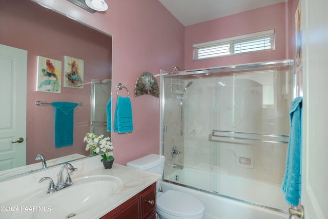 full bathroom featuring vanity, toilet, and bath / shower combo with glass door