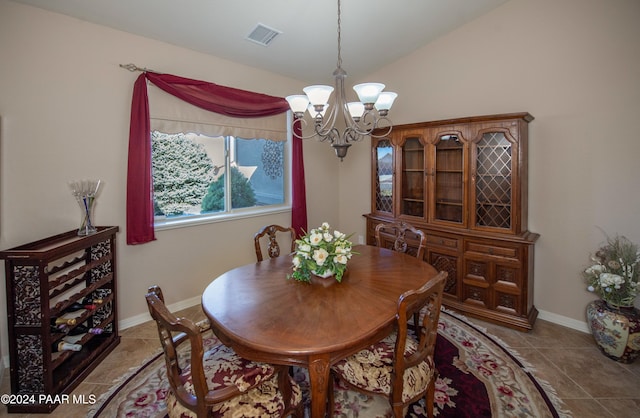 tiled dining area featuring an inviting chandelier and vaulted ceiling