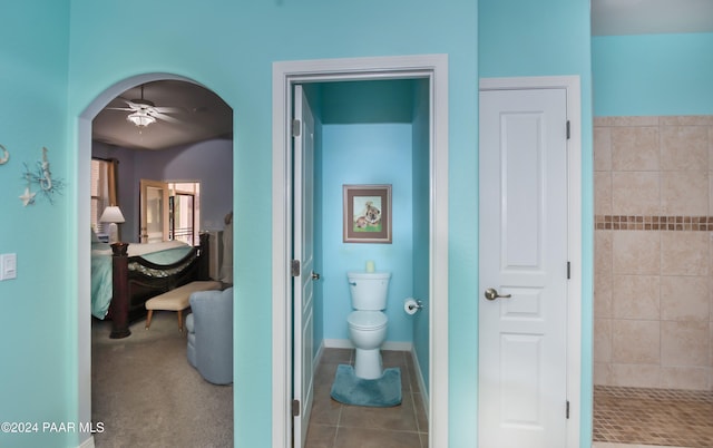 bathroom with tile patterned flooring, ceiling fan, toilet, and tiled shower