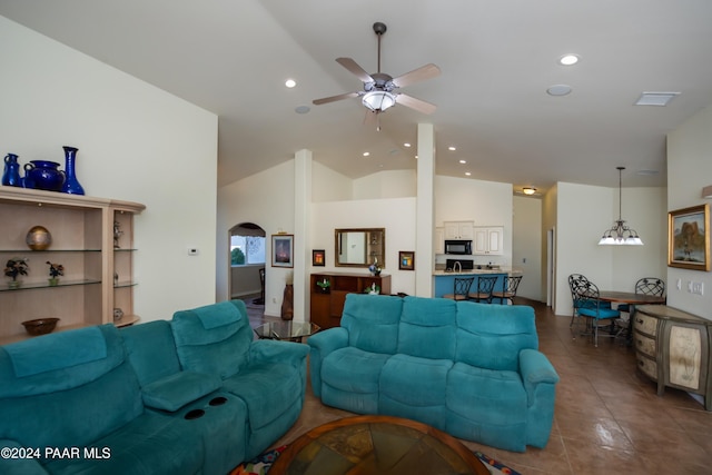 living room with ceiling fan with notable chandelier, dark tile patterned flooring, and lofted ceiling