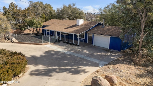 view of front facade with a garage, concrete driveway, a shingled roof, and a chimney