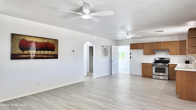 5640 N Burke Blvd, Rimrock, AZ 86335 - kitchen with stainless steel gas range, a ceiling fan, arched walkways, brown cabinets, and under cabinet range hood