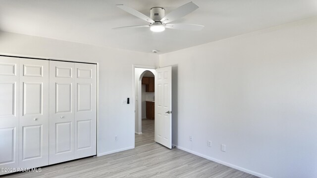 5640 N Burke Blvd, Rimrock, AZ 86335 - unfurnished bedroom with arched walkways, baseboards, a closet, light wood-type flooring, and ceiling fan
