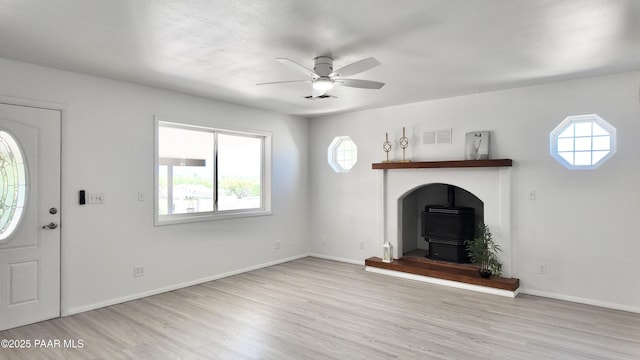 5640 N Burke Blvd, Rimrock, AZ 86335 - unfurnished living room featuring a wood stove, a ceiling fan, healthy amount of natural light, and wood finished floors