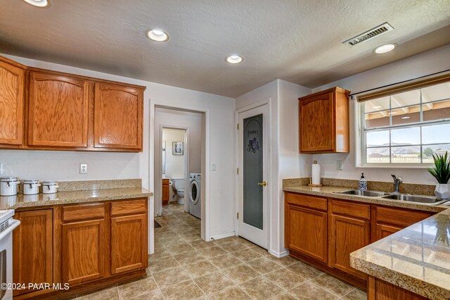 kitchen with a textured ceiling, washer / dryer, and sink