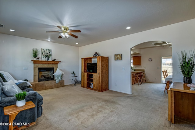 carpeted living room with a tile fireplace and ceiling fan