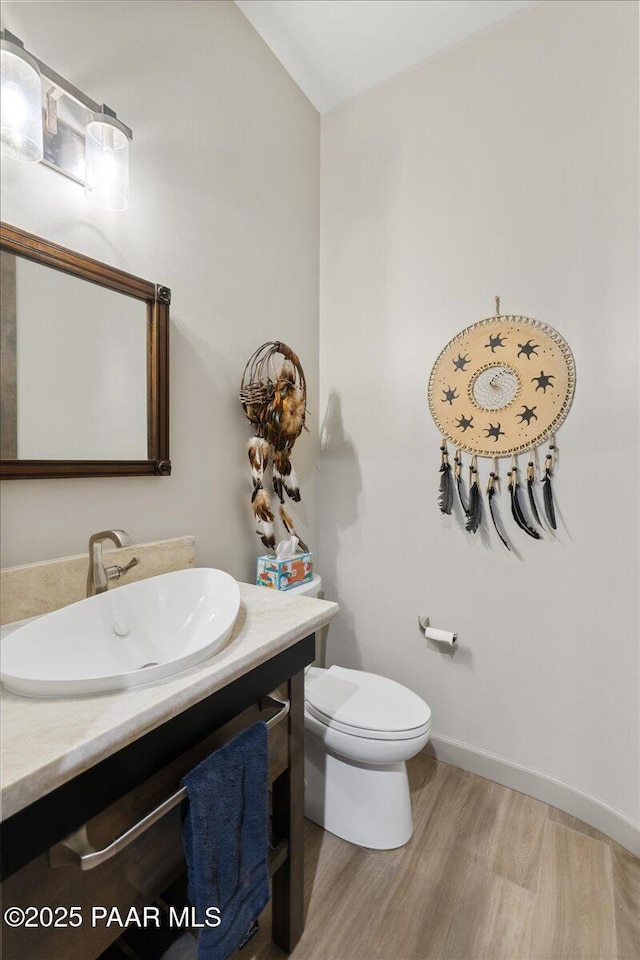 bathroom with toilet, baseboards, wood finished floors, and vanity