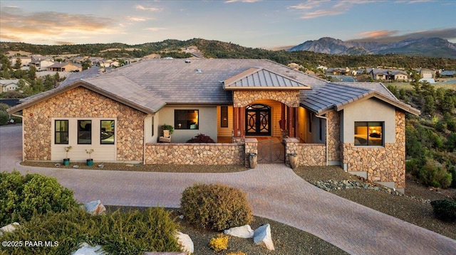 ranch-style home with a gate, a mountain view, stucco siding, and stone siding