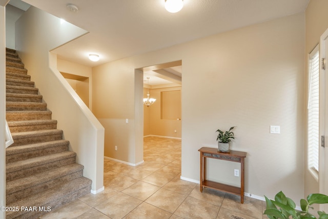 entrance foyer featuring light tile patterned floors, baseboards, stairway, and a chandelier