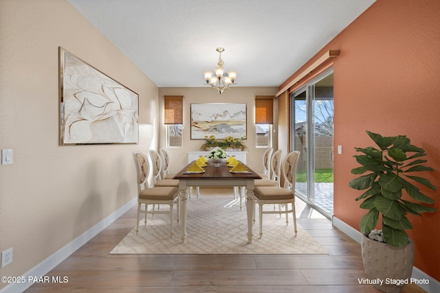 dining space featuring baseboards, an inviting chandelier, and wood finished floors