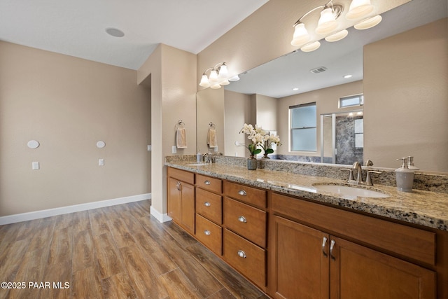 bathroom with double vanity, wood finished floors, baseboards, and a sink