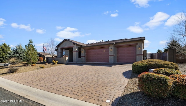 single story home with stucco siding, an attached garage, decorative driveway, and fence