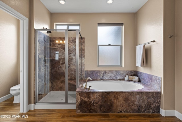 full bath featuring a bath, wood finished floors, baseboards, a shower stall, and toilet