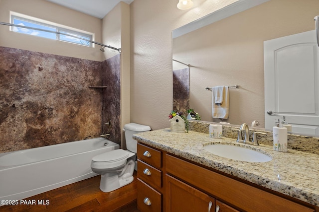 bathroom with toilet, wood finished floors, bathing tub / shower combination, vanity, and a textured wall