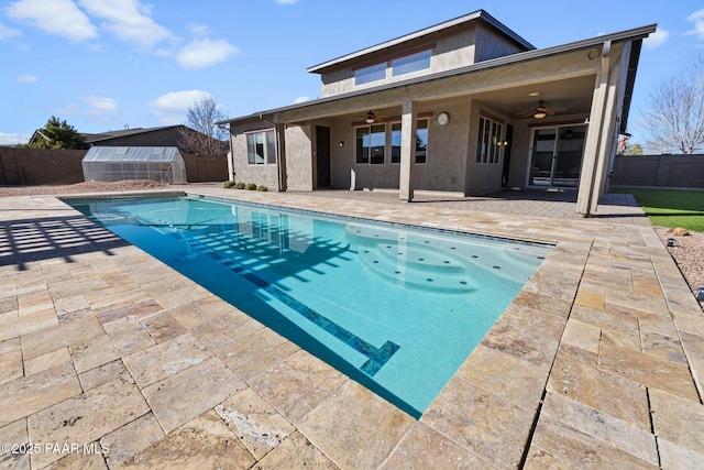 view of swimming pool featuring a patio, a fenced backyard, an outdoor structure, and ceiling fan