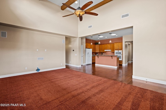 unfurnished living room with baseboards, visible vents, dark colored carpet, and ceiling fan