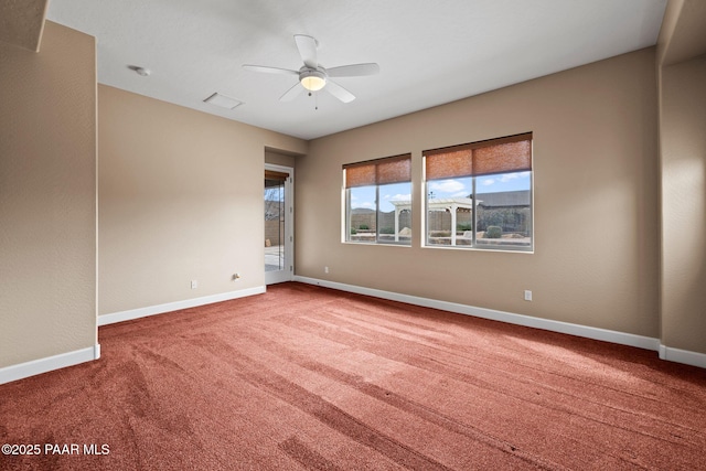 carpeted empty room featuring visible vents, a ceiling fan, and baseboards