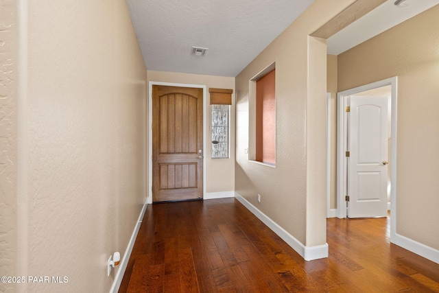 doorway to outside featuring visible vents, a textured ceiling, dark wood-type flooring, and baseboards