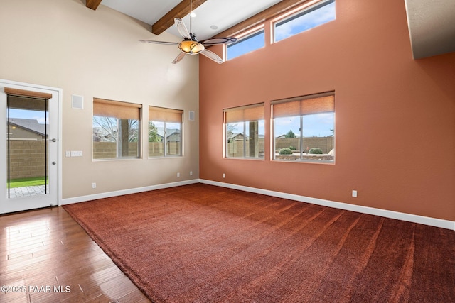 spare room with beam ceiling, a healthy amount of sunlight, and baseboards