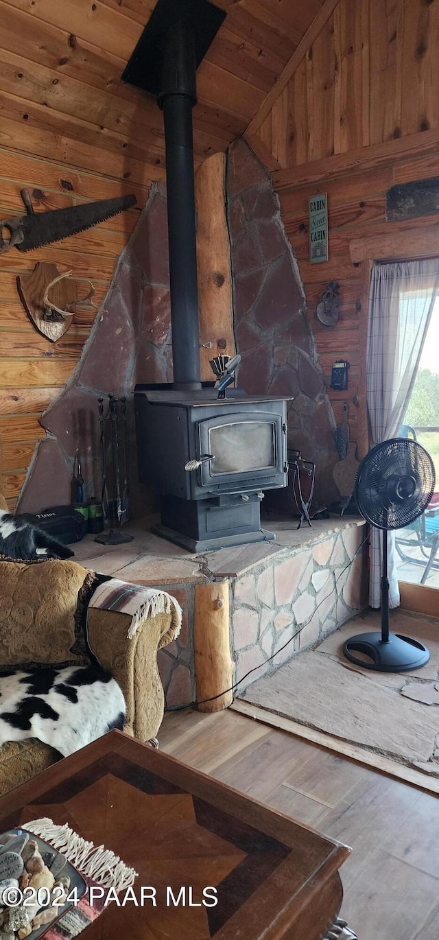 room details featuring a wood stove, wood walls, wooden ceiling, and hardwood / wood-style flooring