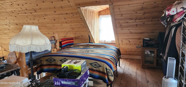 bedroom with hardwood / wood-style flooring and wood walls